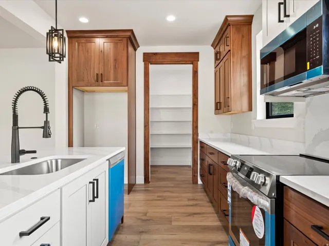Modern kitchen featuring white and wood-finish cabinetry with black hardware, white countertops, and wood-finish flooring