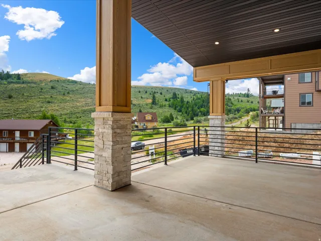 Expansive concrete patio featuring a black metal railing and stone-clad support pillars