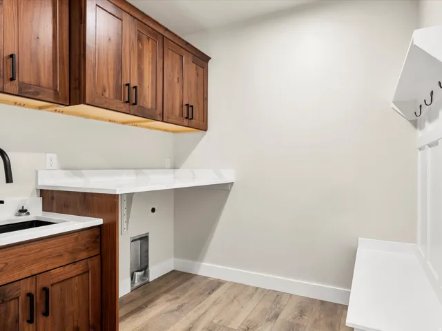 Laundry area with wood-finish flooring, white walls, and built-in white cabinetry featuring a bench