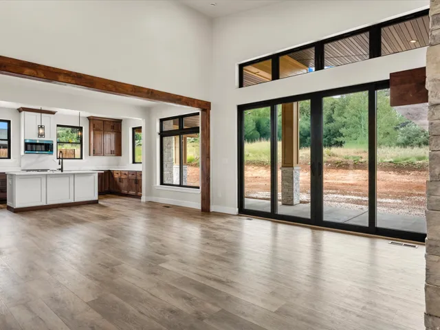 Spacious interior featuring wood-finish flooring, a kitchen with white and wood cabinetry, and a large central island