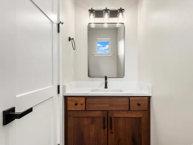 Vanity featuring a dark wood-finish cabinet with black hardware, white countertop, and an undermount sink