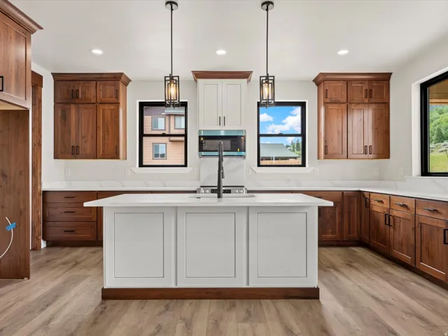Modern kitchen featuring a central island with a built-in sink and matte black faucet, complemented by two contemporary pendant lights