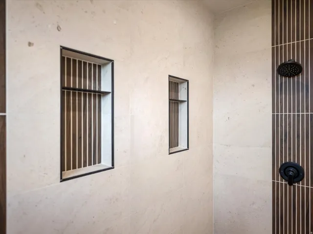 Shower with light-toned rectangular tile walls and contrasting dark wood-finish vertical slat accent tiling