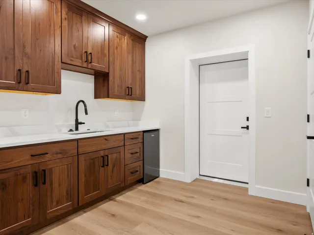 Wet bar featuring wood-finish cabinetry, white countertops, and a built-in beverage refrigerator