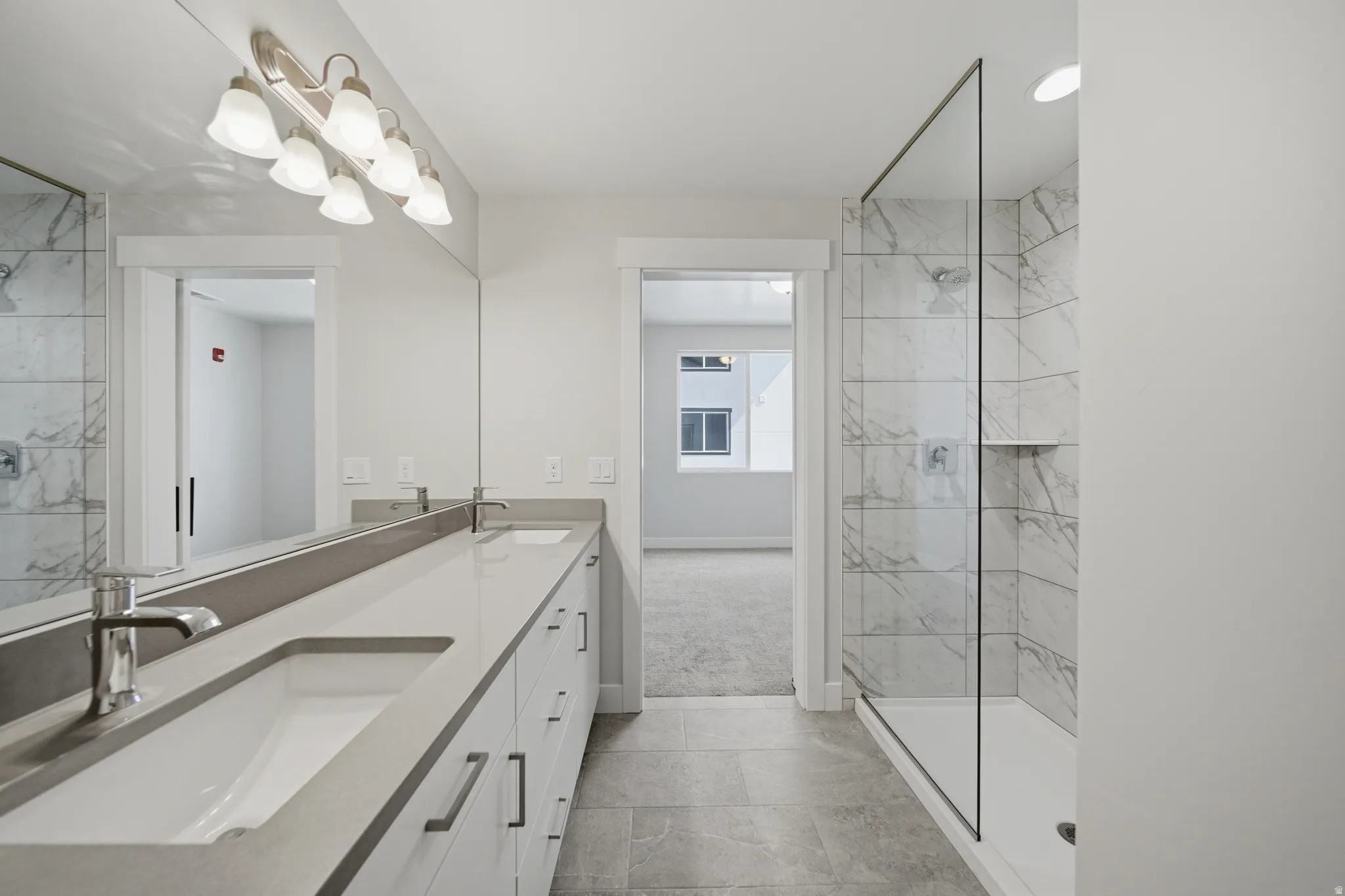 Double vanity featuring light countertops, undermount sinks, and chrome faucets