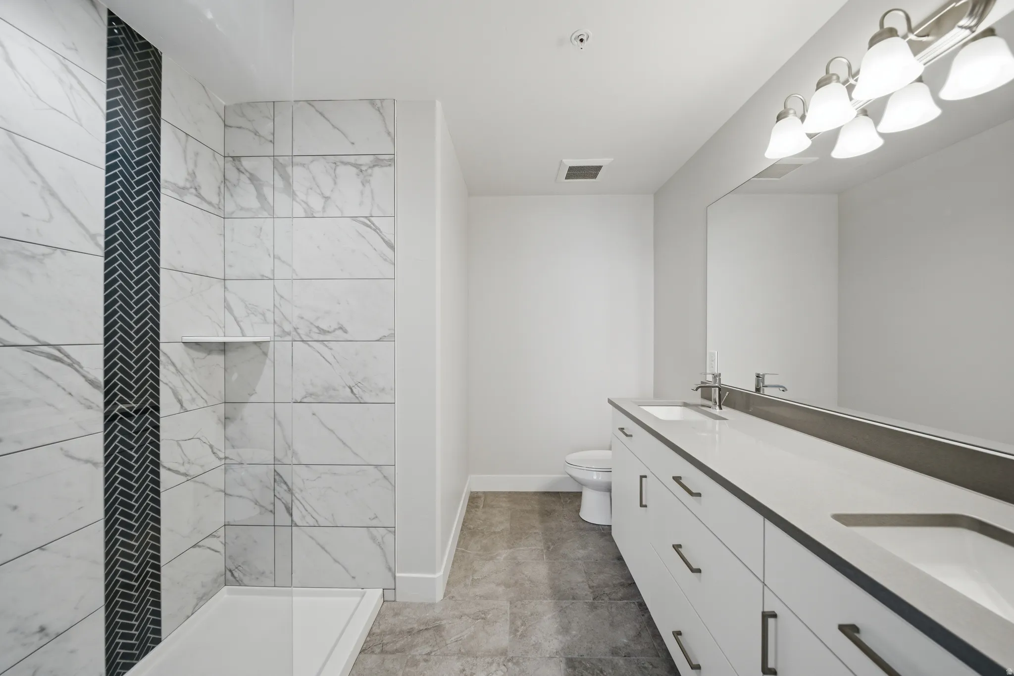 Contemporary bathroom featuring a dual vanity with rectangular undermount sinks, a spacious shower with large format tile, and a decorative herringbone tile accent