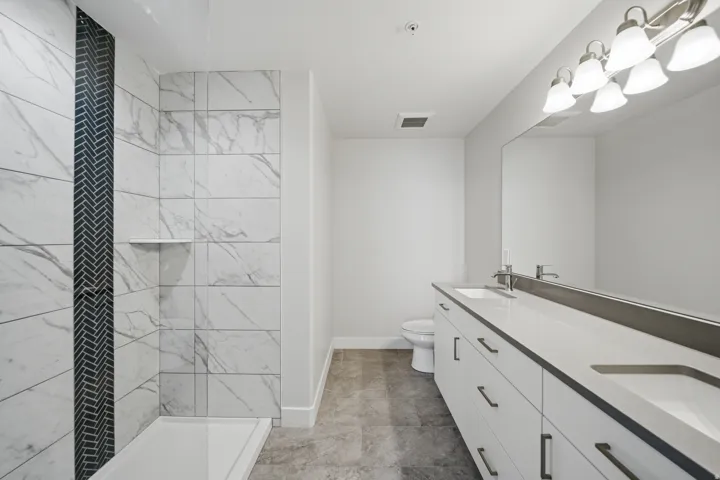 Contemporary bathroom featuring a dual vanity with rectangular undermount sinks, a spacious shower with large format tile, and a decorative herringbone tile accent