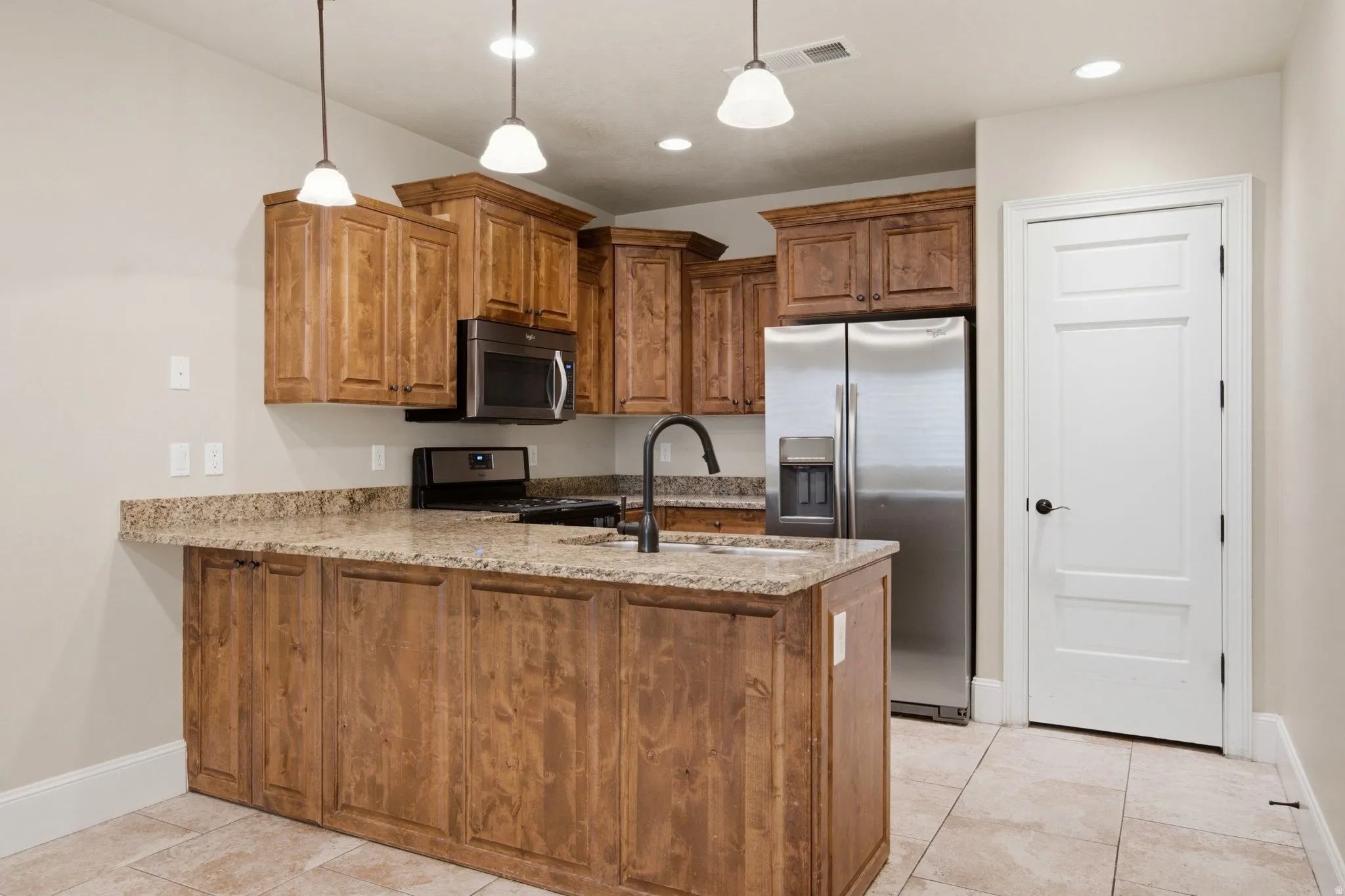 Kitchen featuring wood-finish cabinetry, speckled countertops, and stainless steel appliances