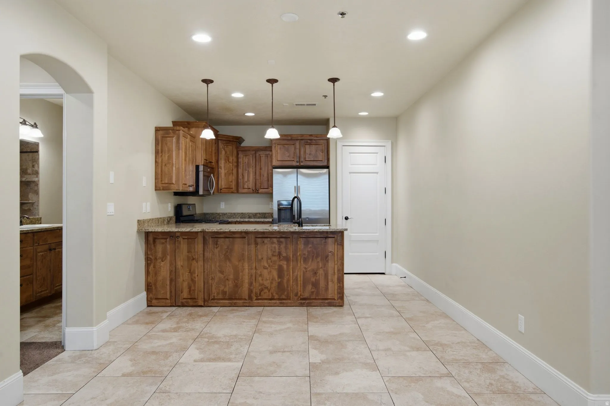 Kitchen area featuring wood cabinetry, stainless steel appliances, and a breakfast bar with pendant lighting