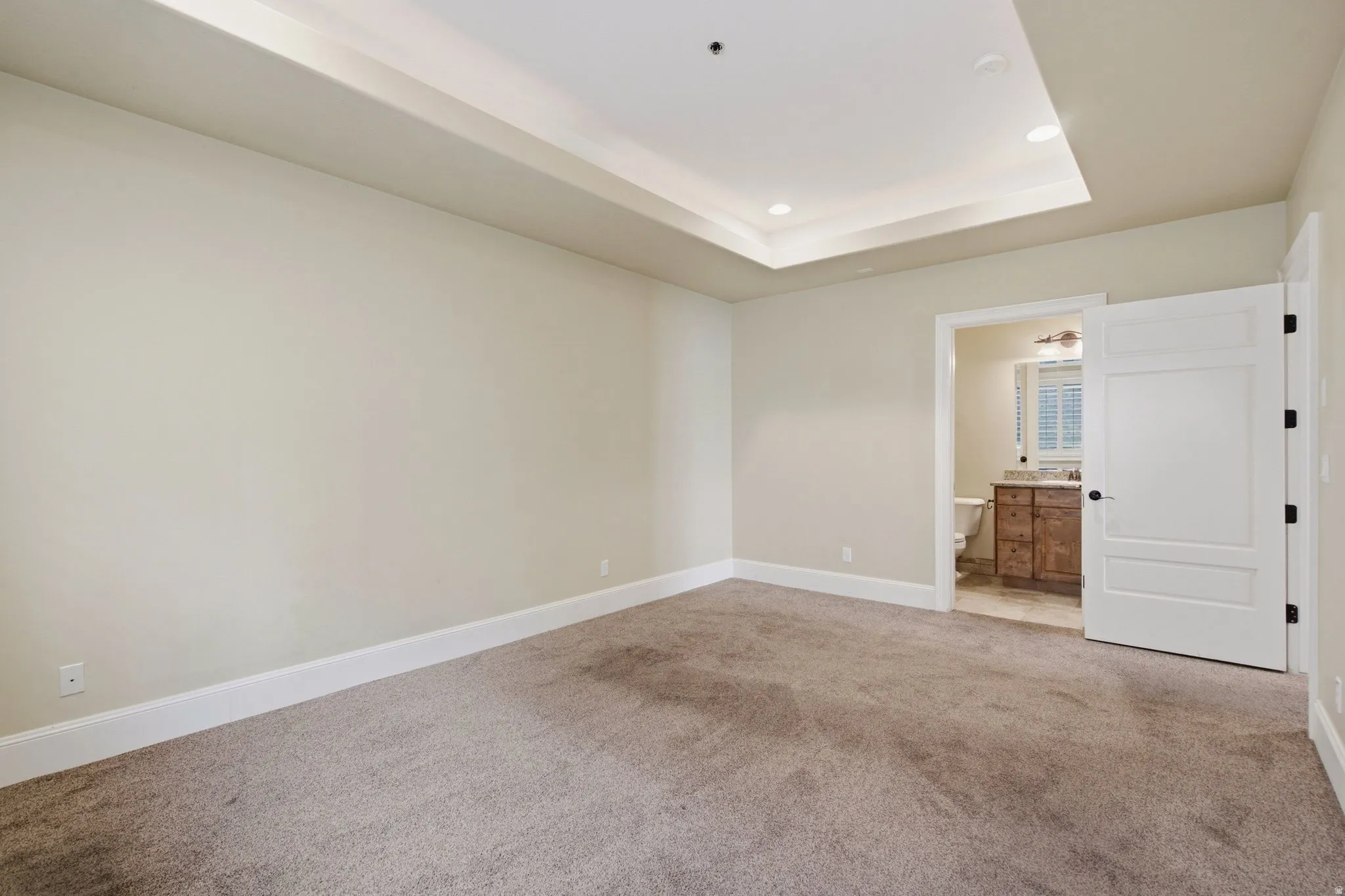 Neutral tone walls with white baseboards and tray ceiling