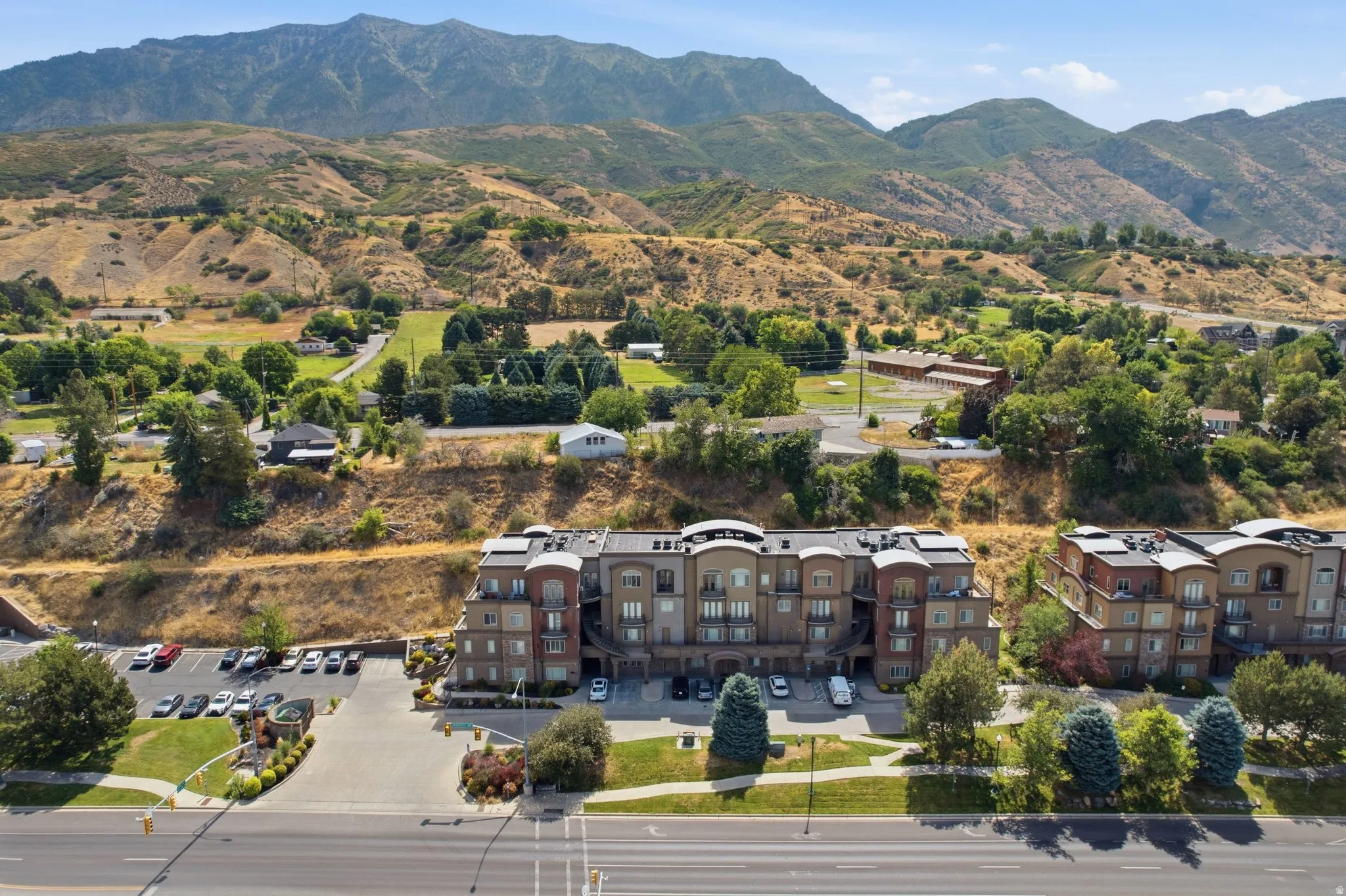 Multi-story residential building featuring balconies, dedicated parking, and manicured landscaping