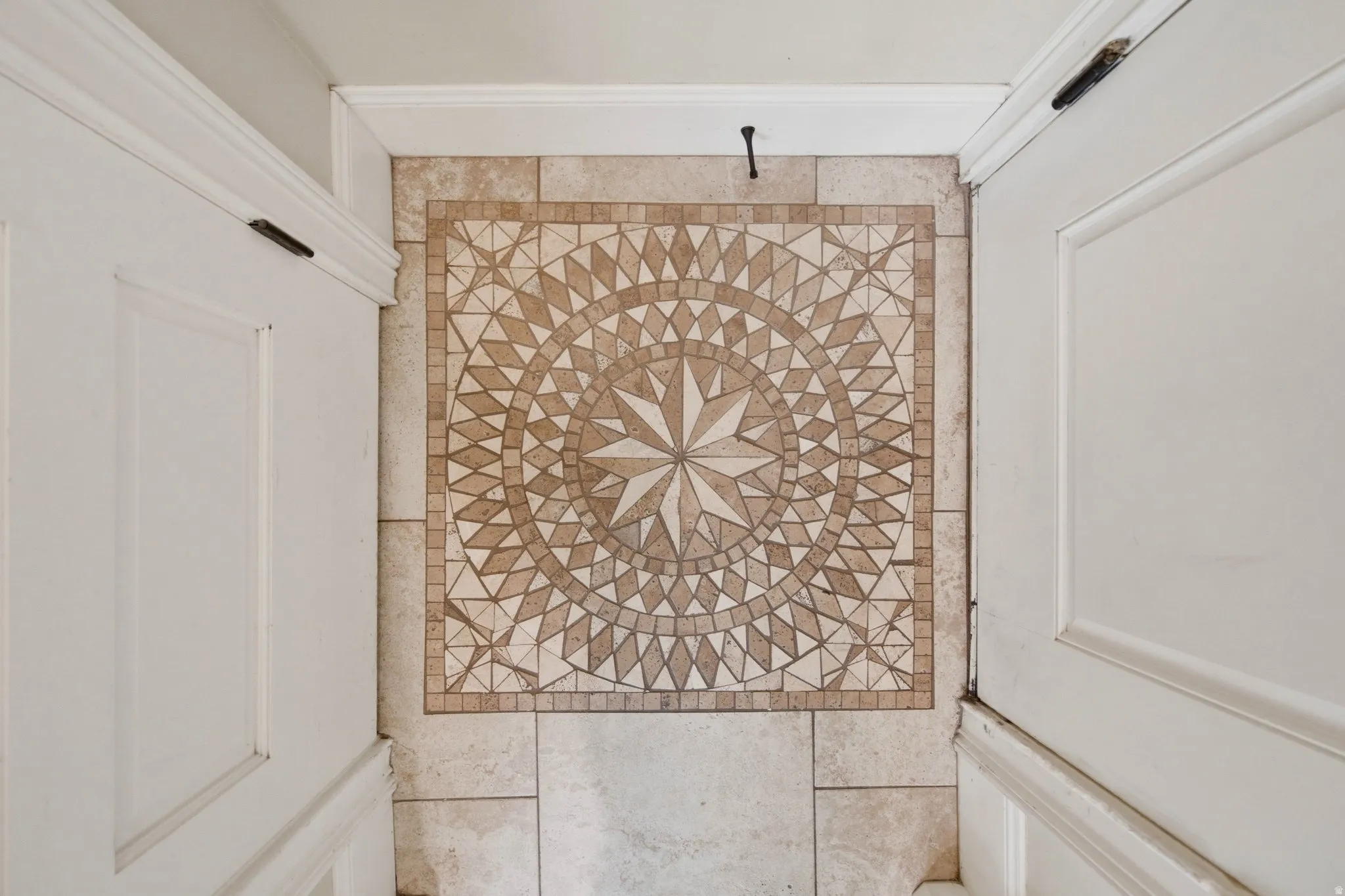 Intricate mosaic tile floor with a central star design, framed by neutral square tiles