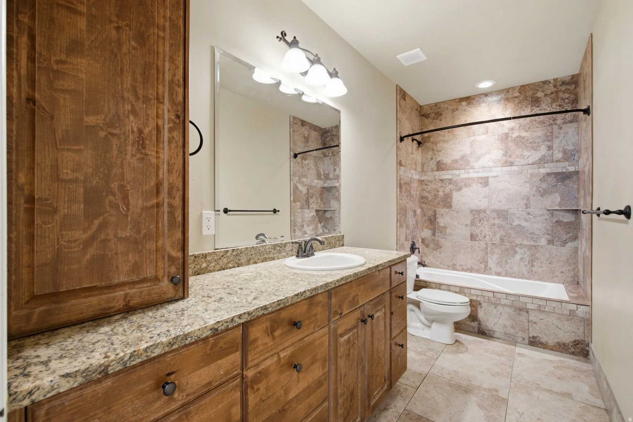 Spacious bathroom featuring a single vanity with a granite-style countertop, wood cabinetry, an integrated sink, and a large wall mirror