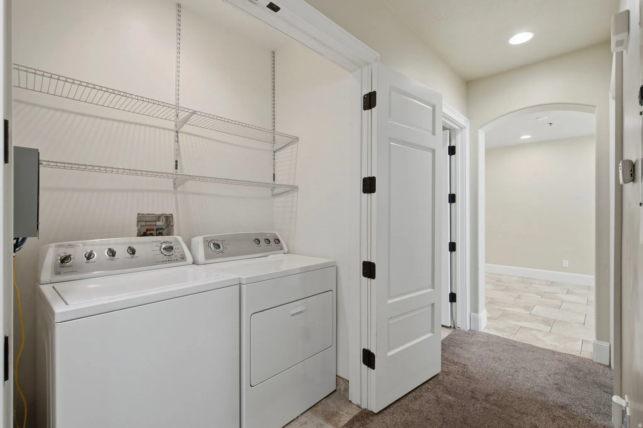 Dedicated laundry area featuring a washer and dryer, integrated wire shelving, and recessed lighting