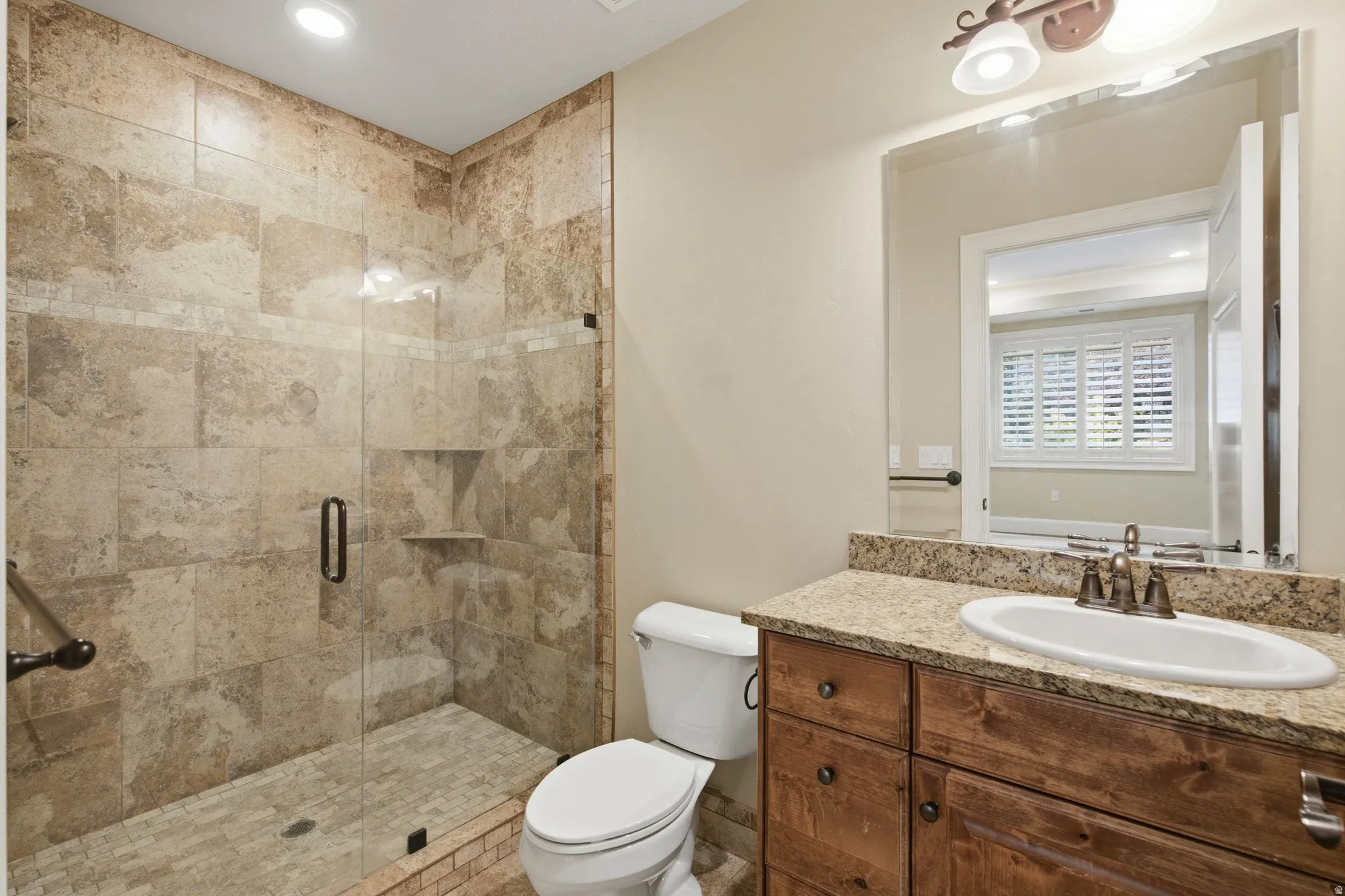 Bathroom featuring a walk-in shower with natural stone tile surround, glass enclosure, and built-in niche