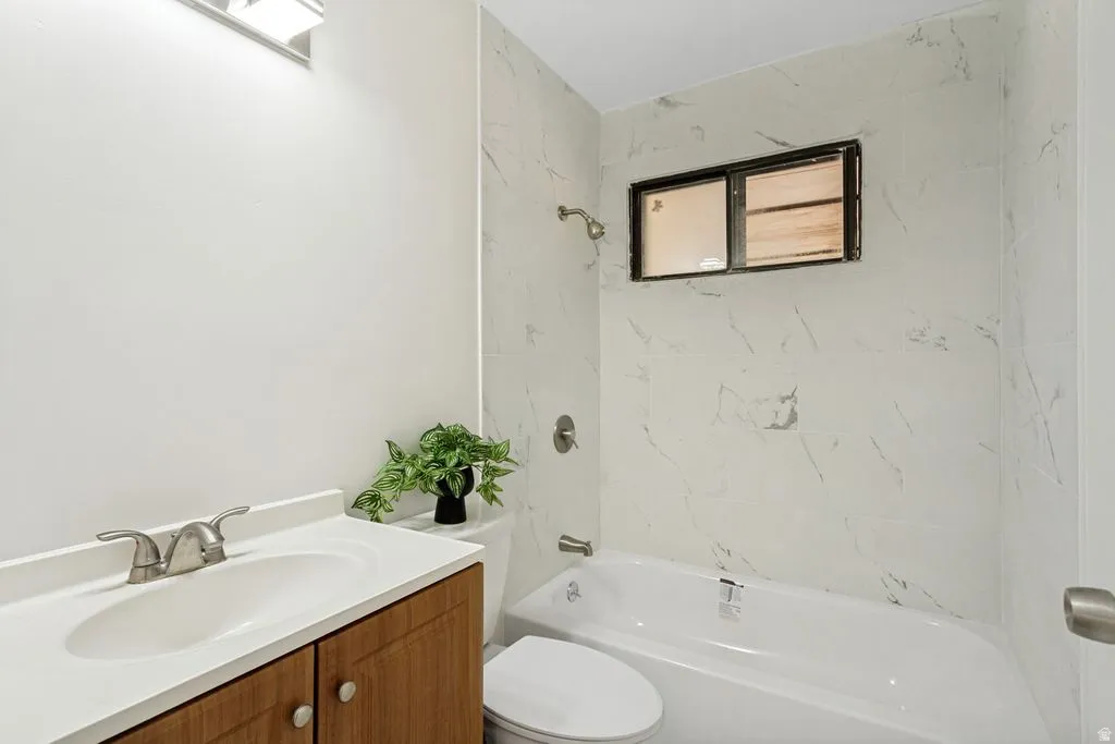Full bathroom featuring a white vanity with a rectangular sink, brushed nickel faucet, and wood-finish cabinetry