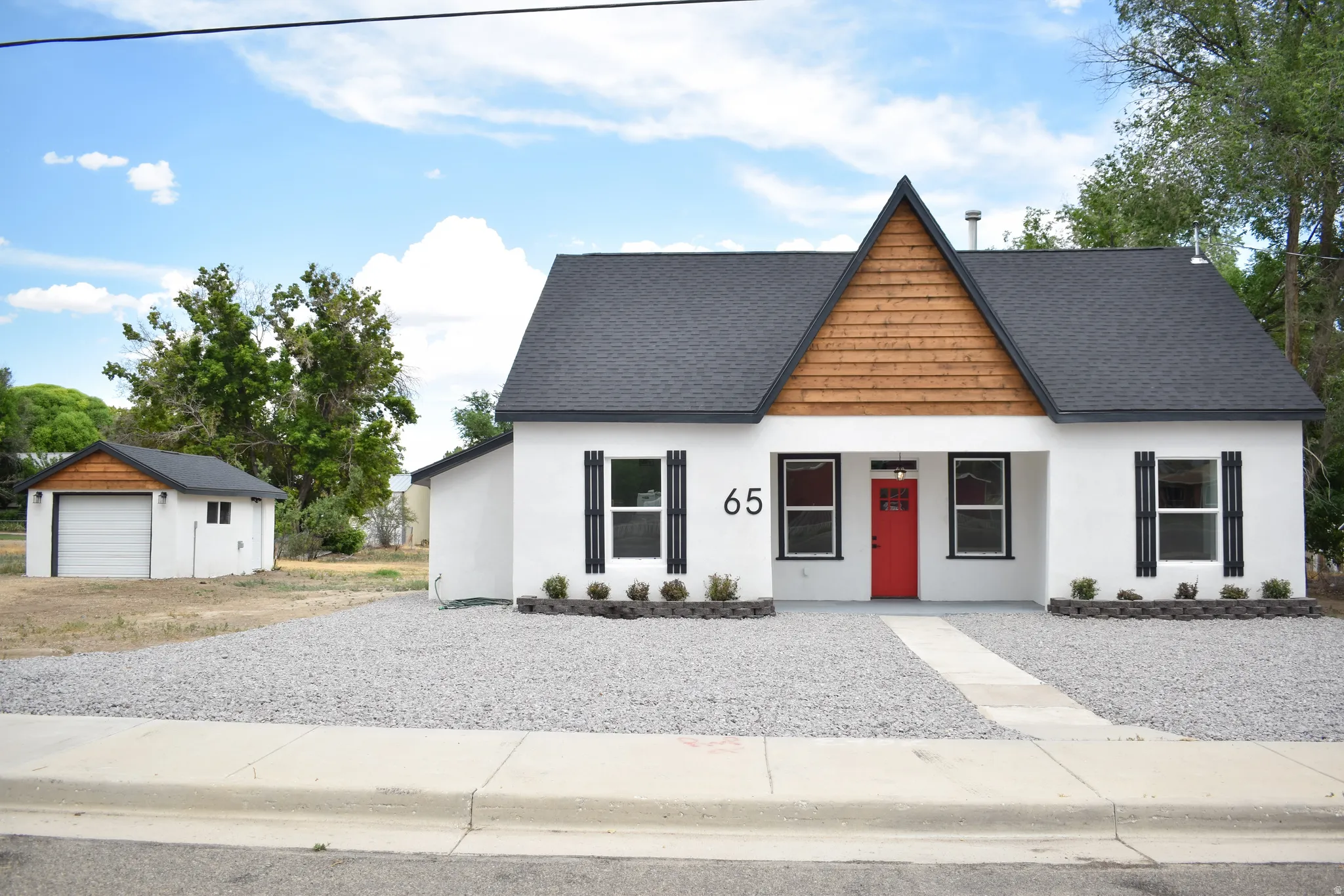White stucco exterior with a striking red entry door and black shutters