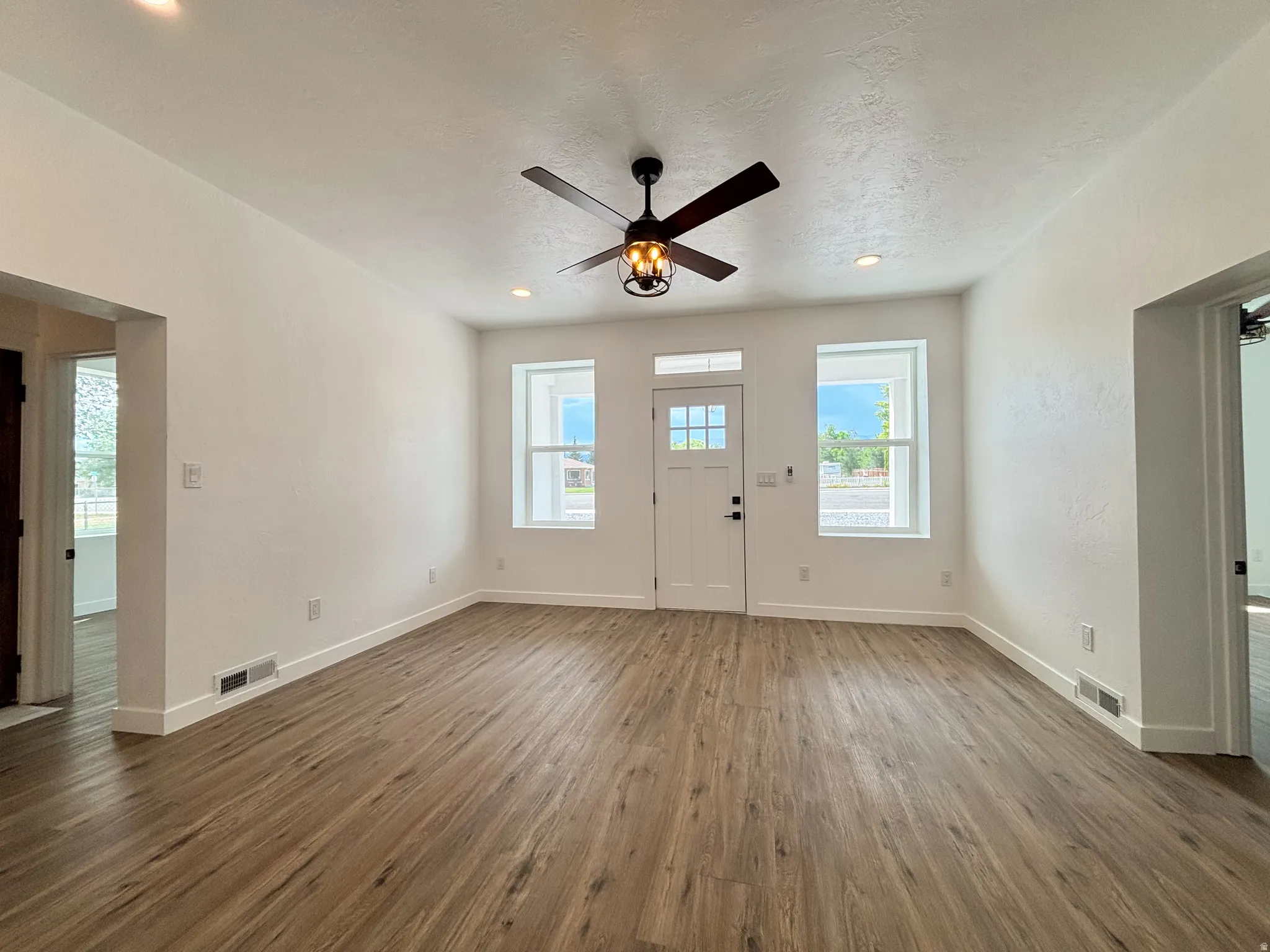 Spacious entry area featuring wood-finish flooring, recessed lighting, and a ceiling fan with integrated lighting