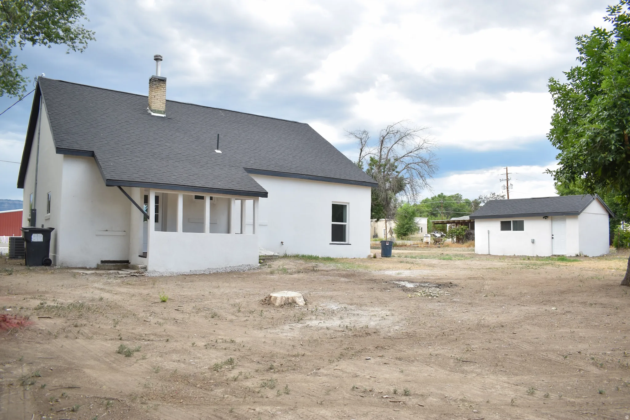 White stucco exterior with a dark shingle roof and an enclosed porch