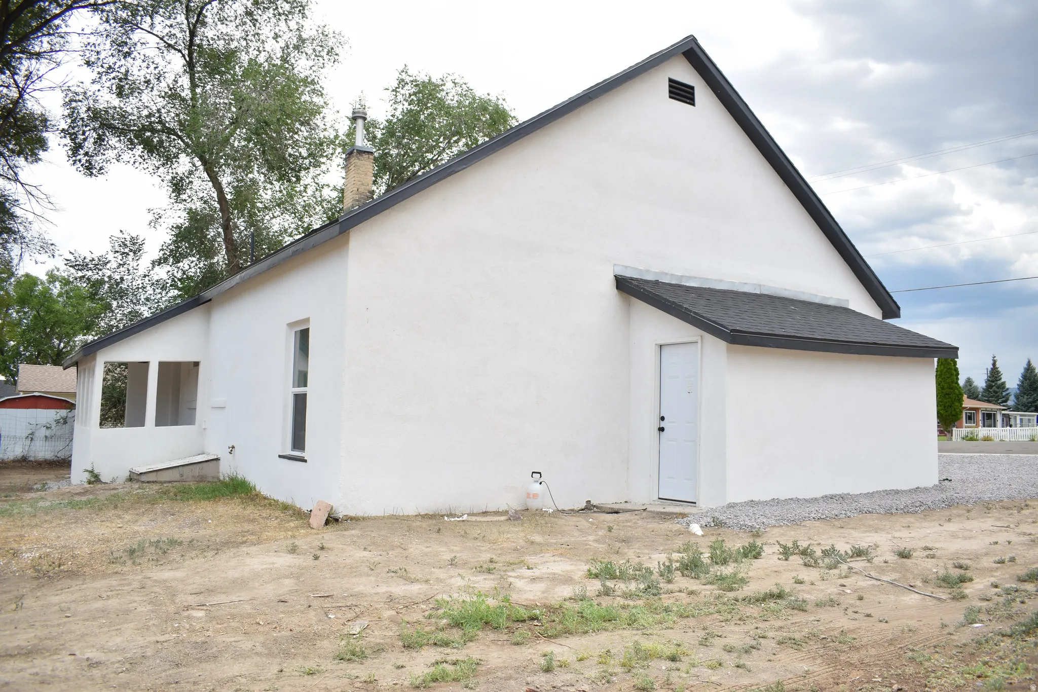 White stucco exterior with a dark shingle roof and a covered entry