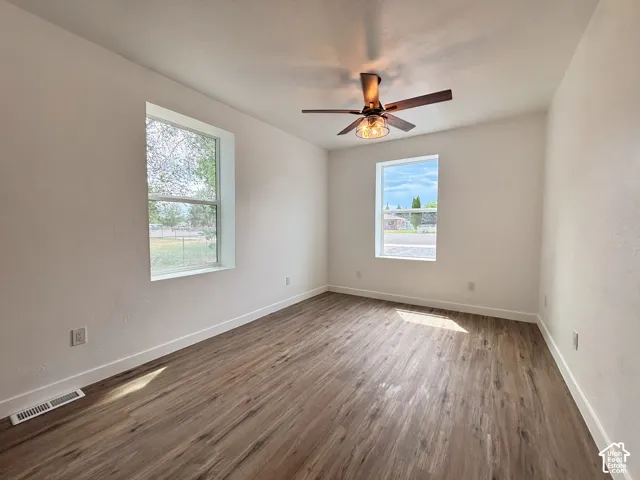 Room with wood-finish flooring, white walls, and a ceiling fan with integrated lighting