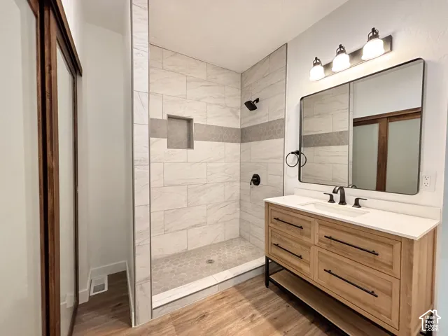 Walk-in shower with tiled walls and a hex tile floor, featuring a built-in niche