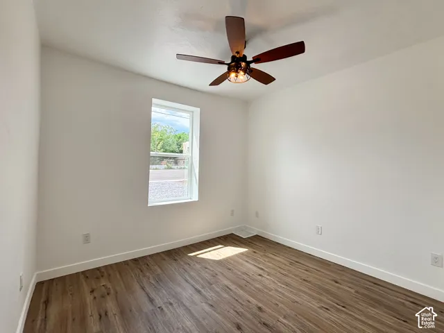 Bright interior space featuring wood-finish flooring, white baseboards, and a contemporary ceiling fan with integrated lighting