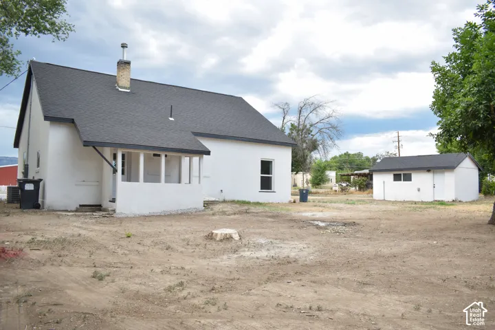 White stucco exterior with a dark shingle roof and an enclosed porch