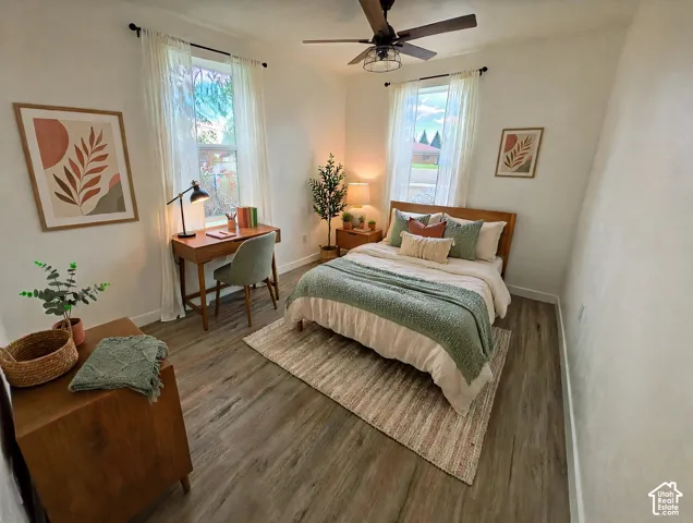 Wood-finish flooring, dual windows with curtain rods, and a ceiling fan with integrated light fixture