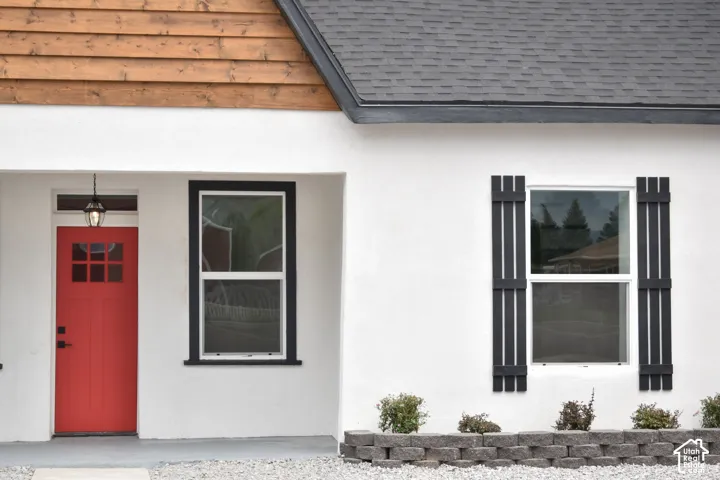 White stucco exterior with a bright red entry door featuring glass panes and a hanging porch light