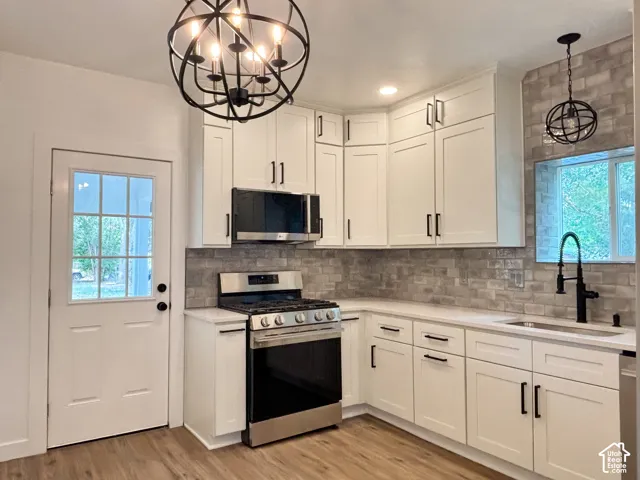 Kitchen featuring white shaker cabinetry, stainless steel appliances, a grey subway tile backsplash, and wood-finish flooring