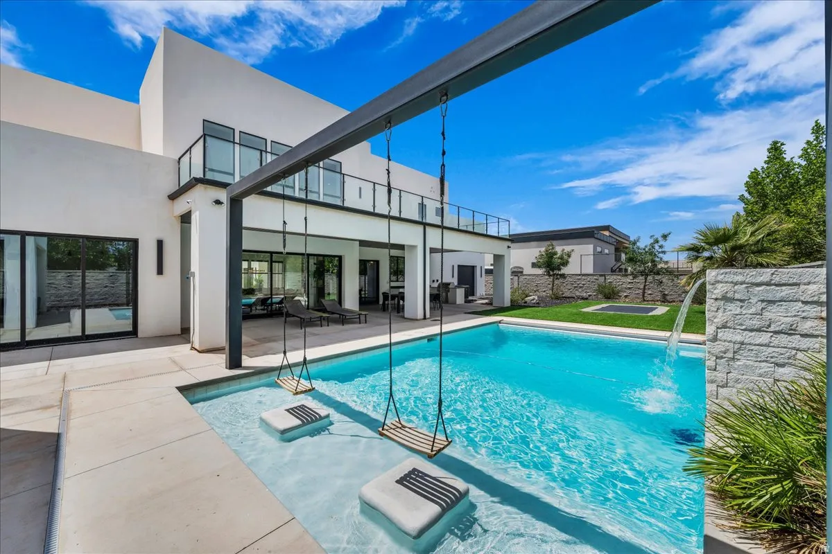 Modern exterior featuring a swimming pool with integrated water swings, a stone-clad waterfall feature, and a sun shelf