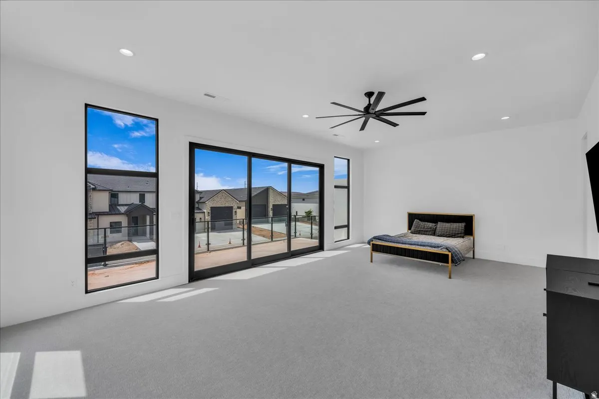 Bright room featuring expansive sliding glass doors, dual vertical windows, recessed lighting, and a modern ceiling fan