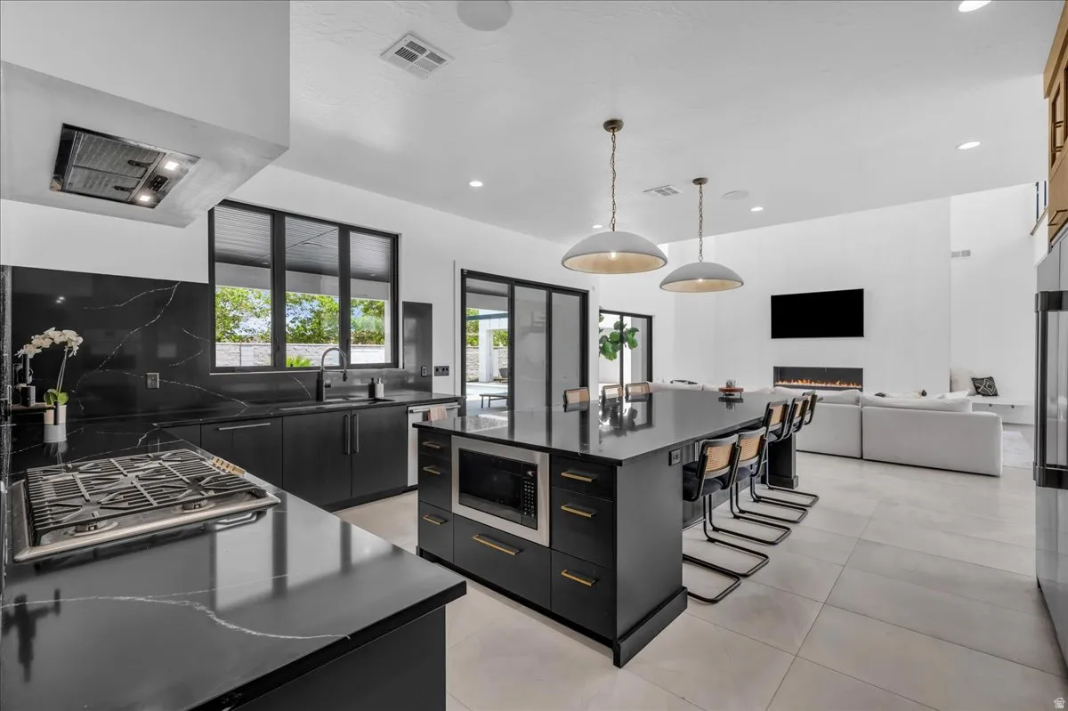 Modern kitchen featuring dark cabinetry, dark countertops with light veining, and a central island with integrated microwave