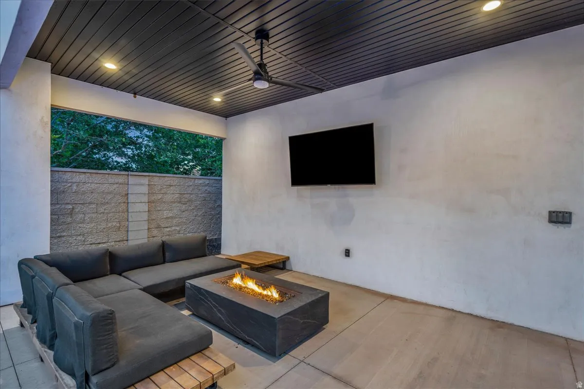 Covered outdoor patio featuring a slatted ceiling with recessed lighting and a ceiling fan