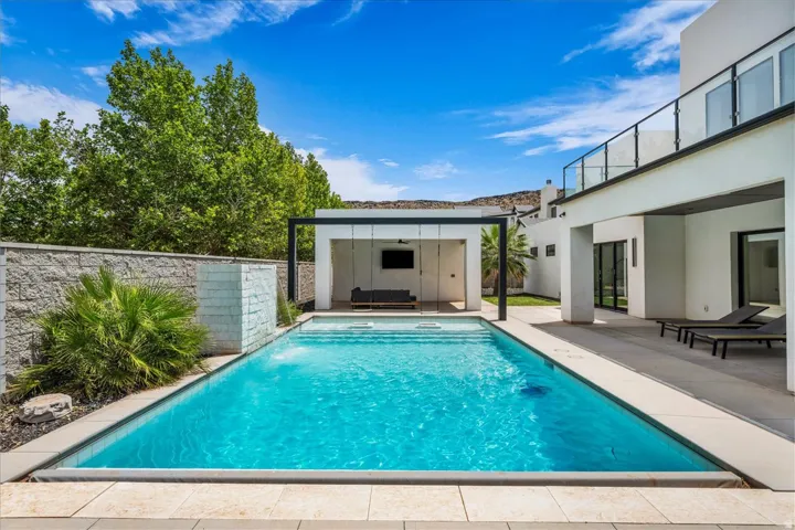 Swimming pool with integrated steps, surrounded by light-toned paving stones