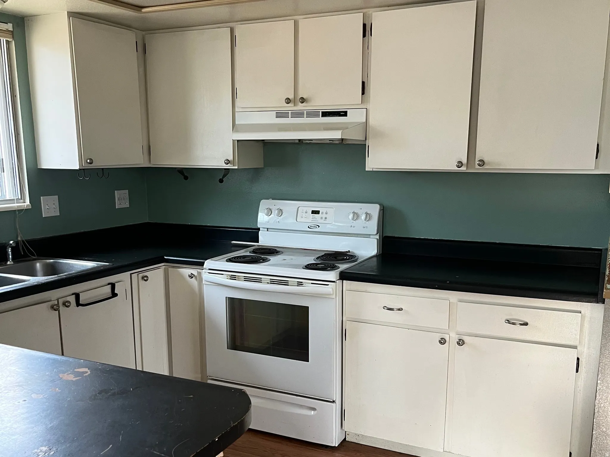 Kitchen featuring white cabinetry, dark countertops, a built-in range, and a double basin sink