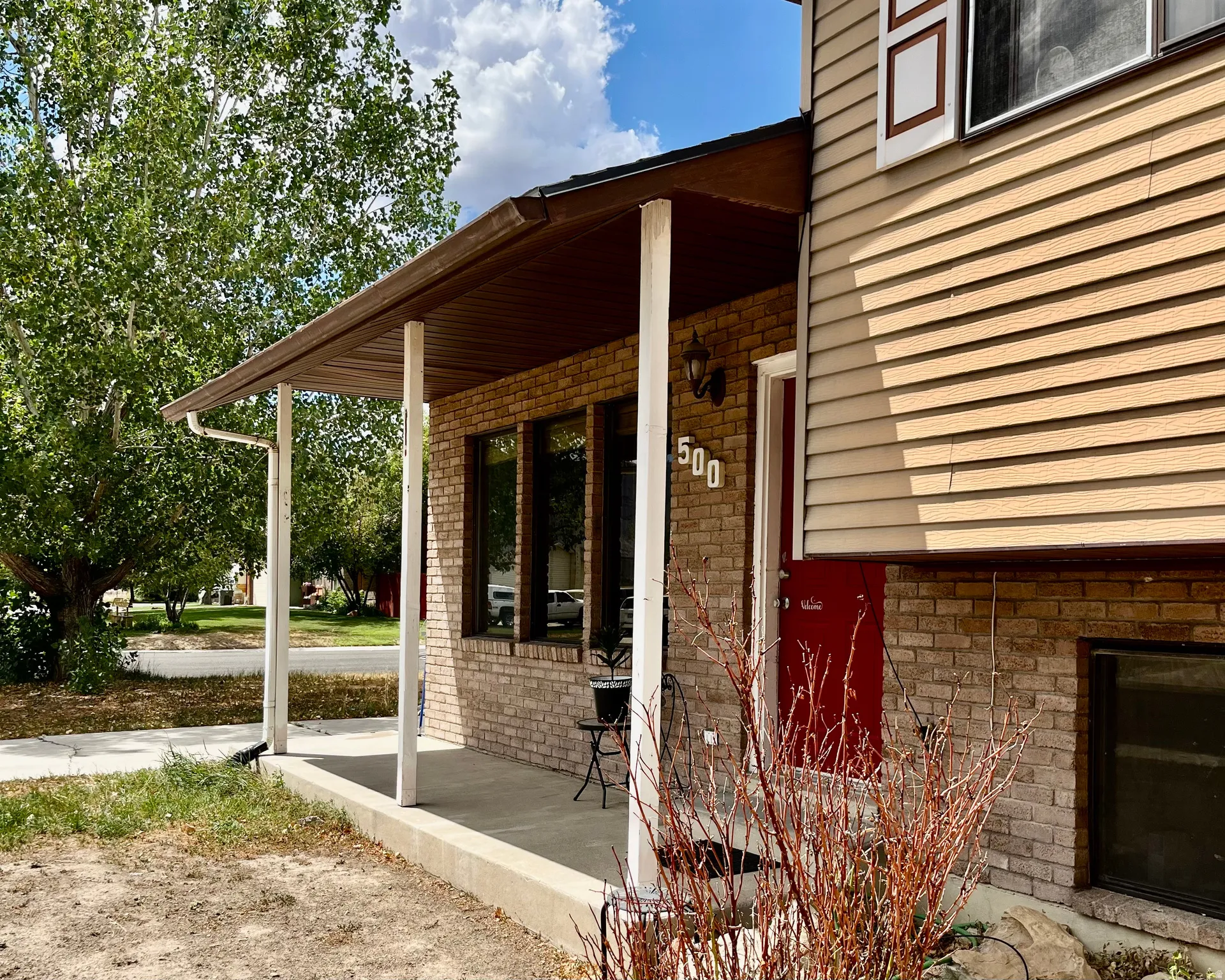Covered porch featuring brick and siding exterior