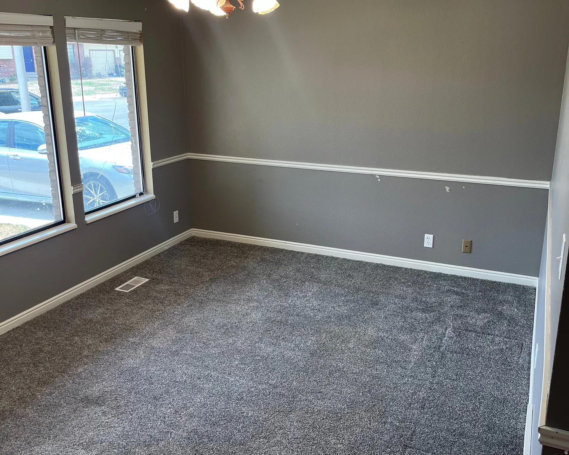 Spacious interior room featuring new gray carpeting, chair rail molding, and multiple windows for a well lite front living room. 13.5' x 10.5'
