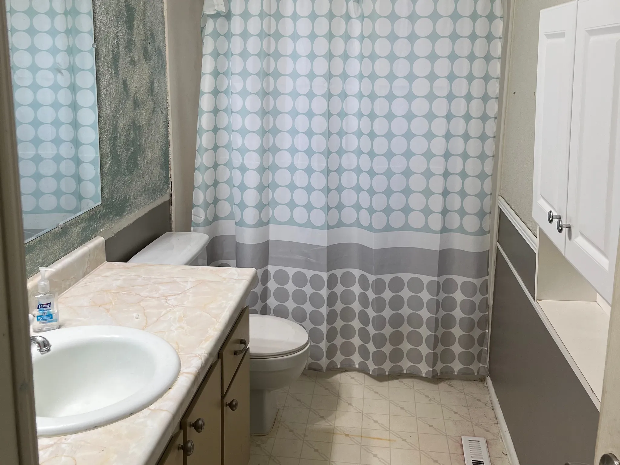 Vanity with integrated sink, wall-mounted mirror, built-in shelving, and white cabinetry.