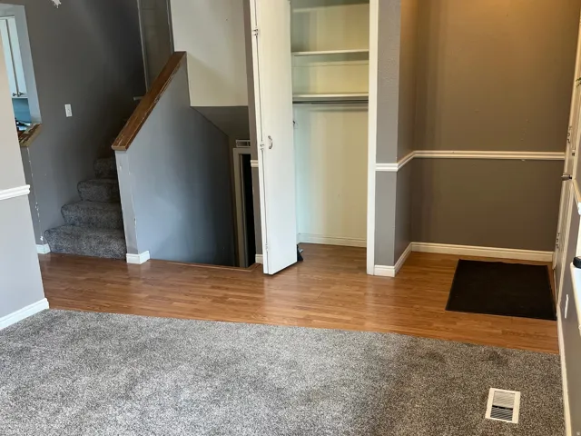 Entryway featuring wood-finish flooring, a carpeted staircase with wood handrail, and white baseboard and chair rail molding. Entry coat closet. Stairs that go up to the 2nd level, and stairs that go down to the basement.