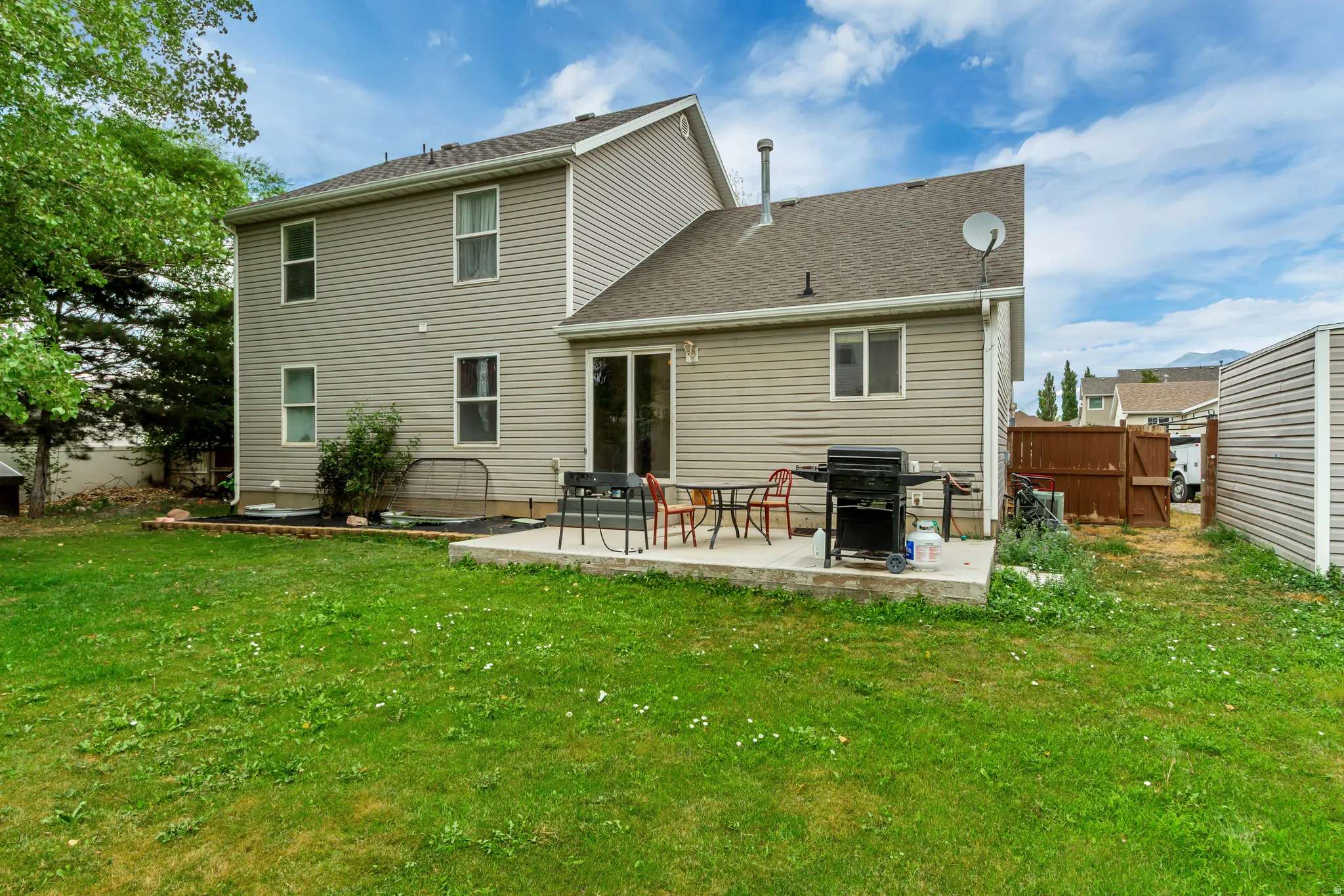 Spacious backyard featuring a concrete patio, sliding glass door access to the interior, and a privacy fence