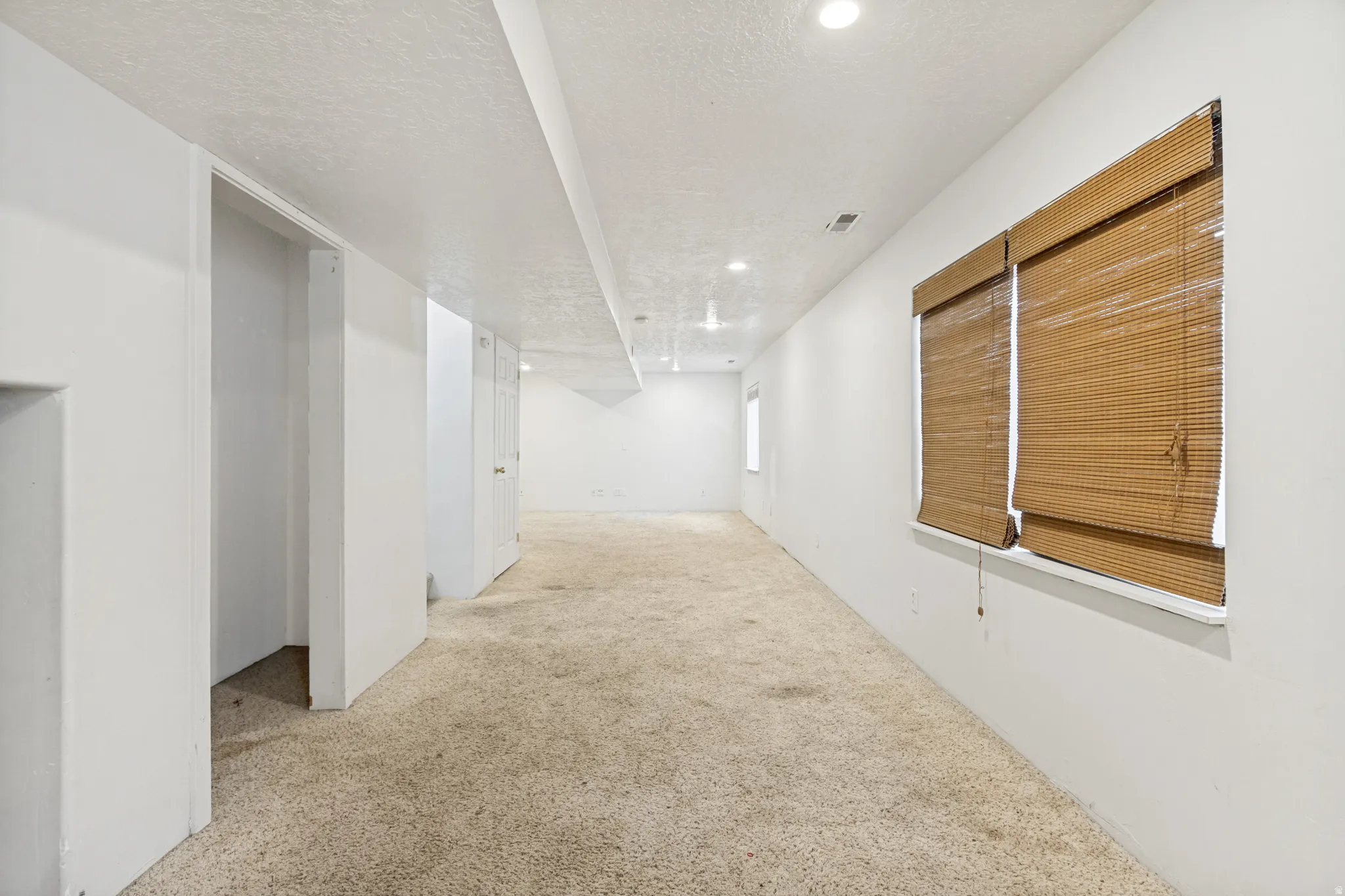 Expansive room featuring recessed lighting, a neutral color palette, and woven wood window treatments