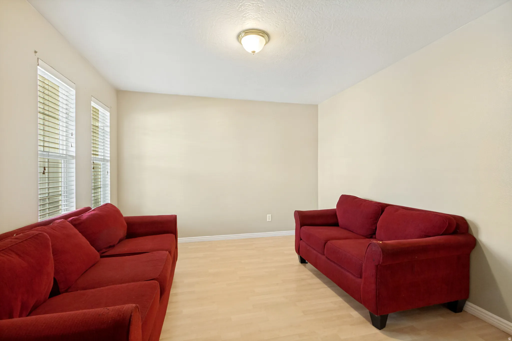 Spacious room featuring light-toned wood-finish flooring and neutral wall paint
