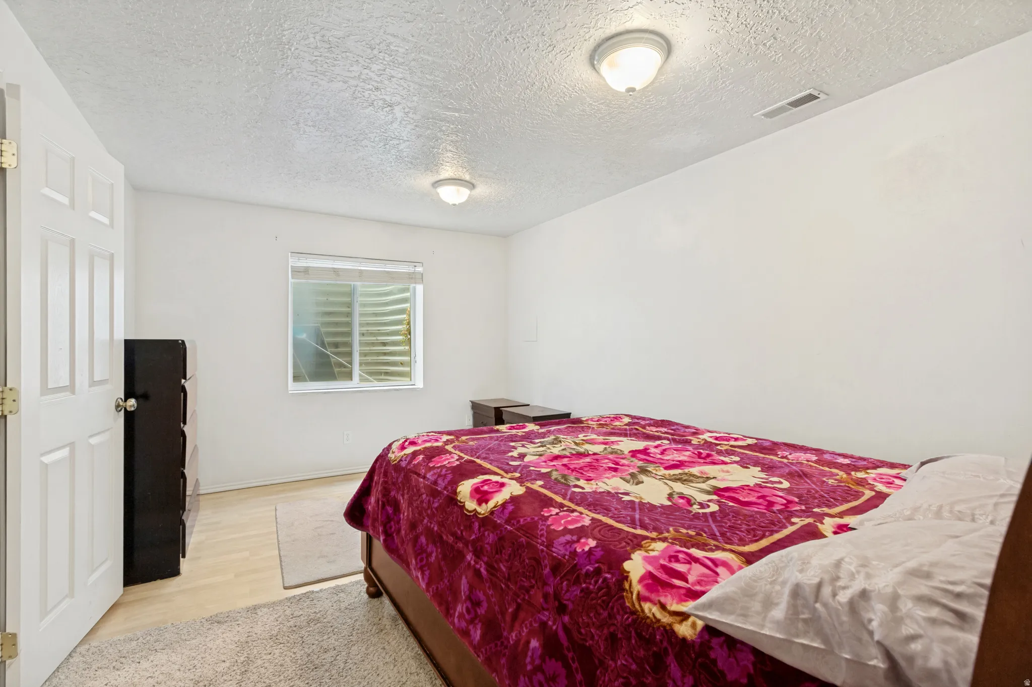 Bright interior space featuring light wood-finish flooring, white walls, and a window with a window well