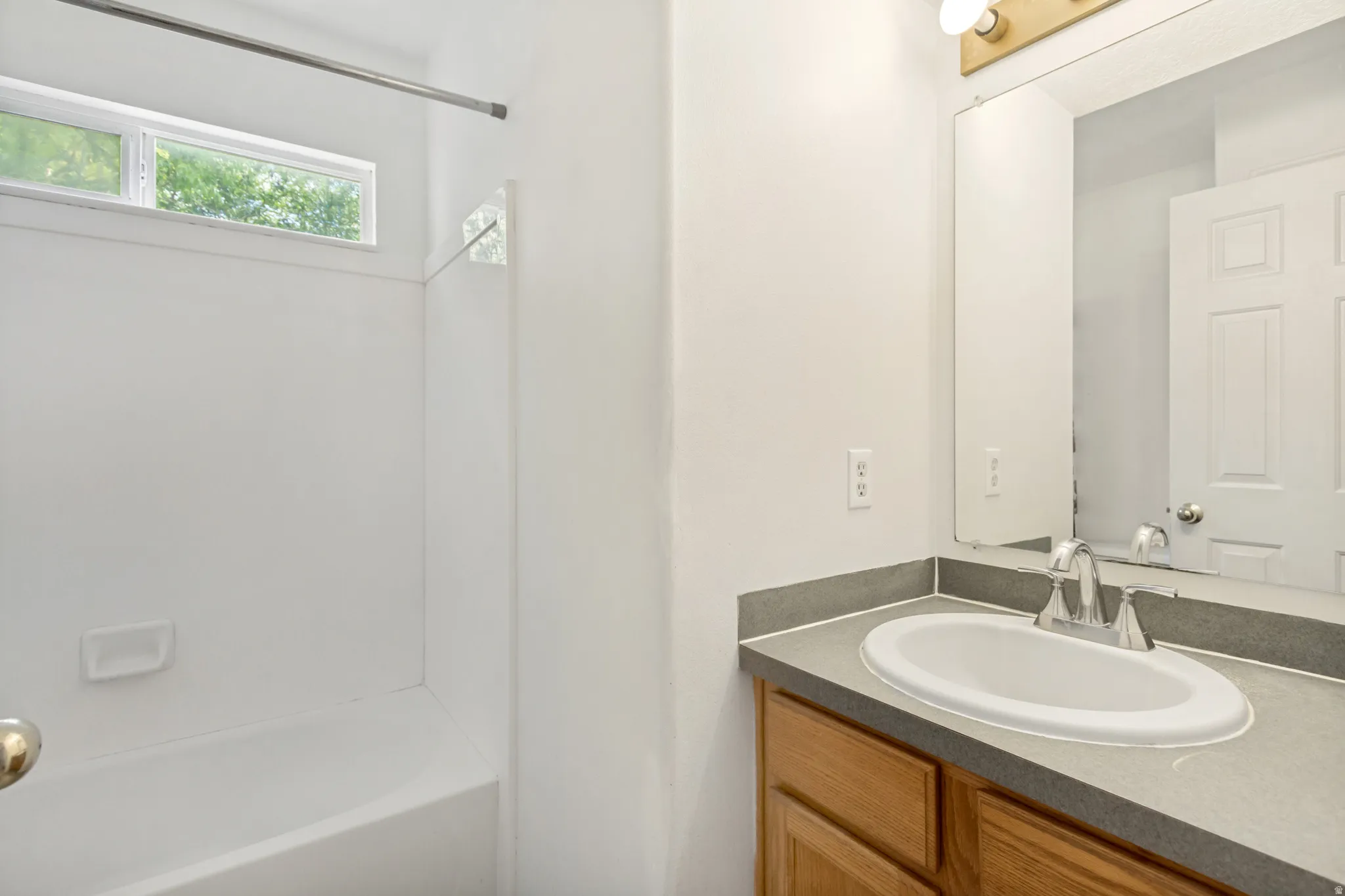 Bathroom vanity featuring a light wood-finish cabinet, a gray countertop, and an integrated oval sink