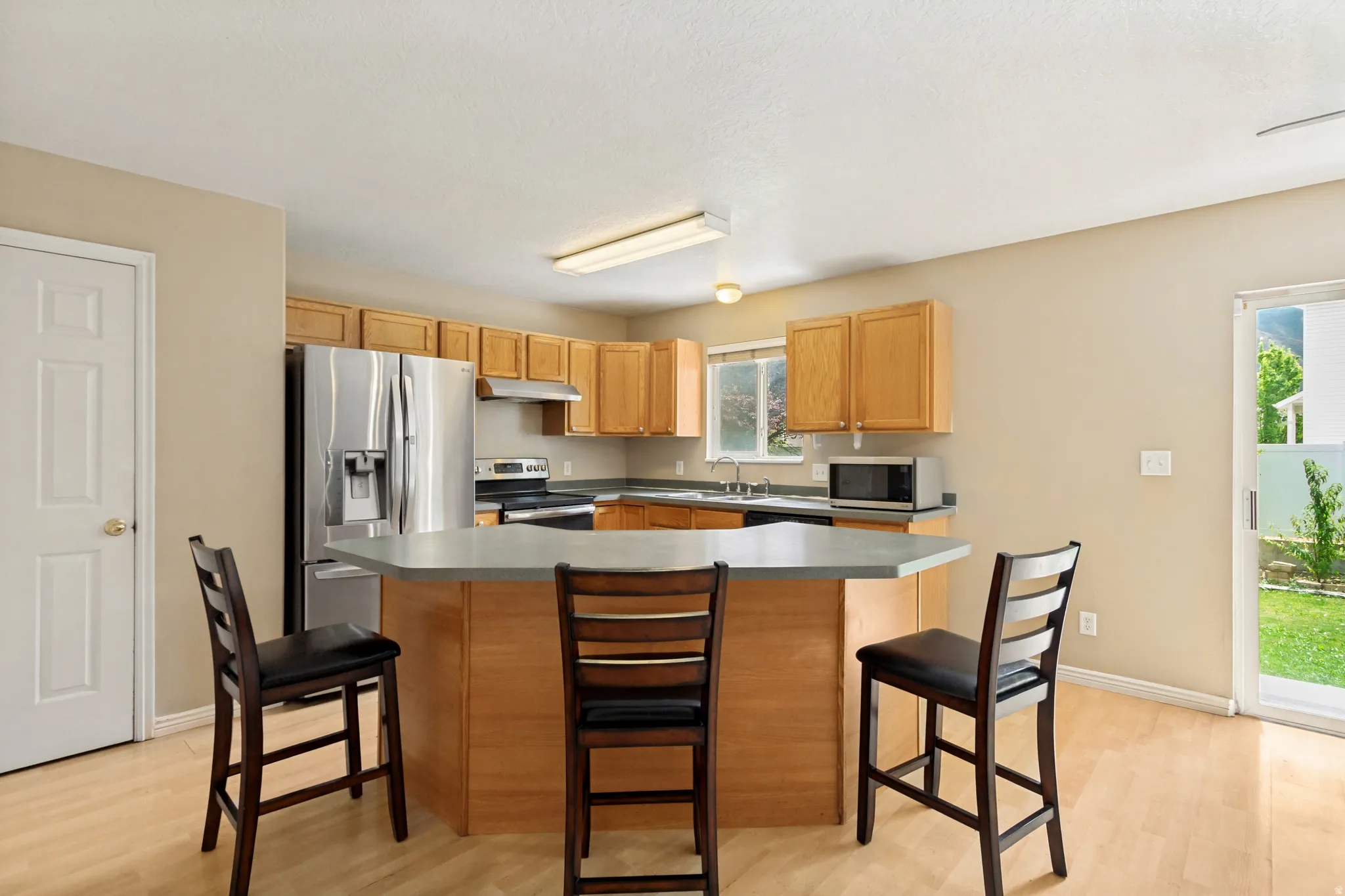 Kitchen featuring light wood cabinetry, stainless steel appliances, a center island with bar seating, and light wood-finish flooring