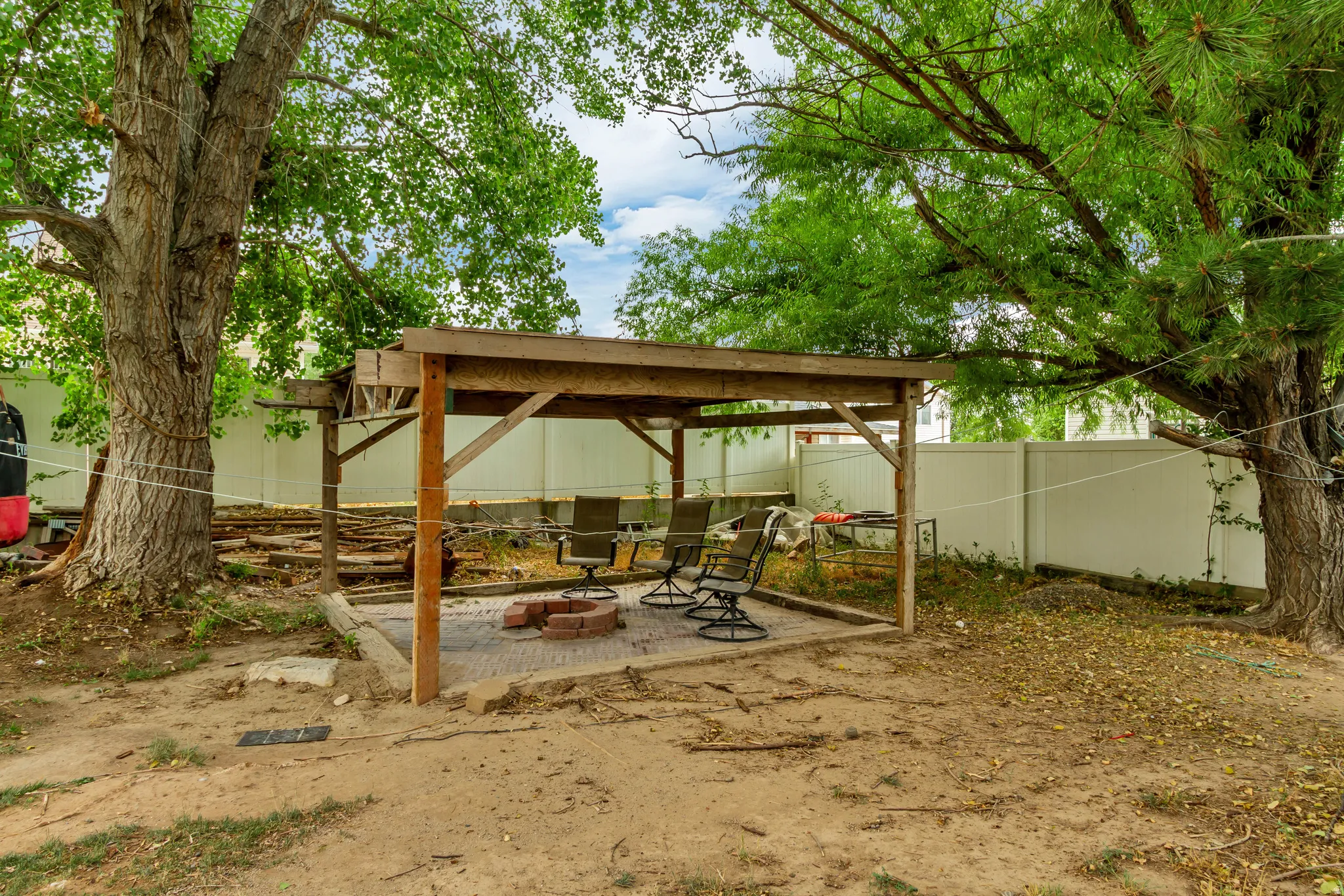 Backyard featuring a covered patio with an exposed wood frame and a brick fire pit