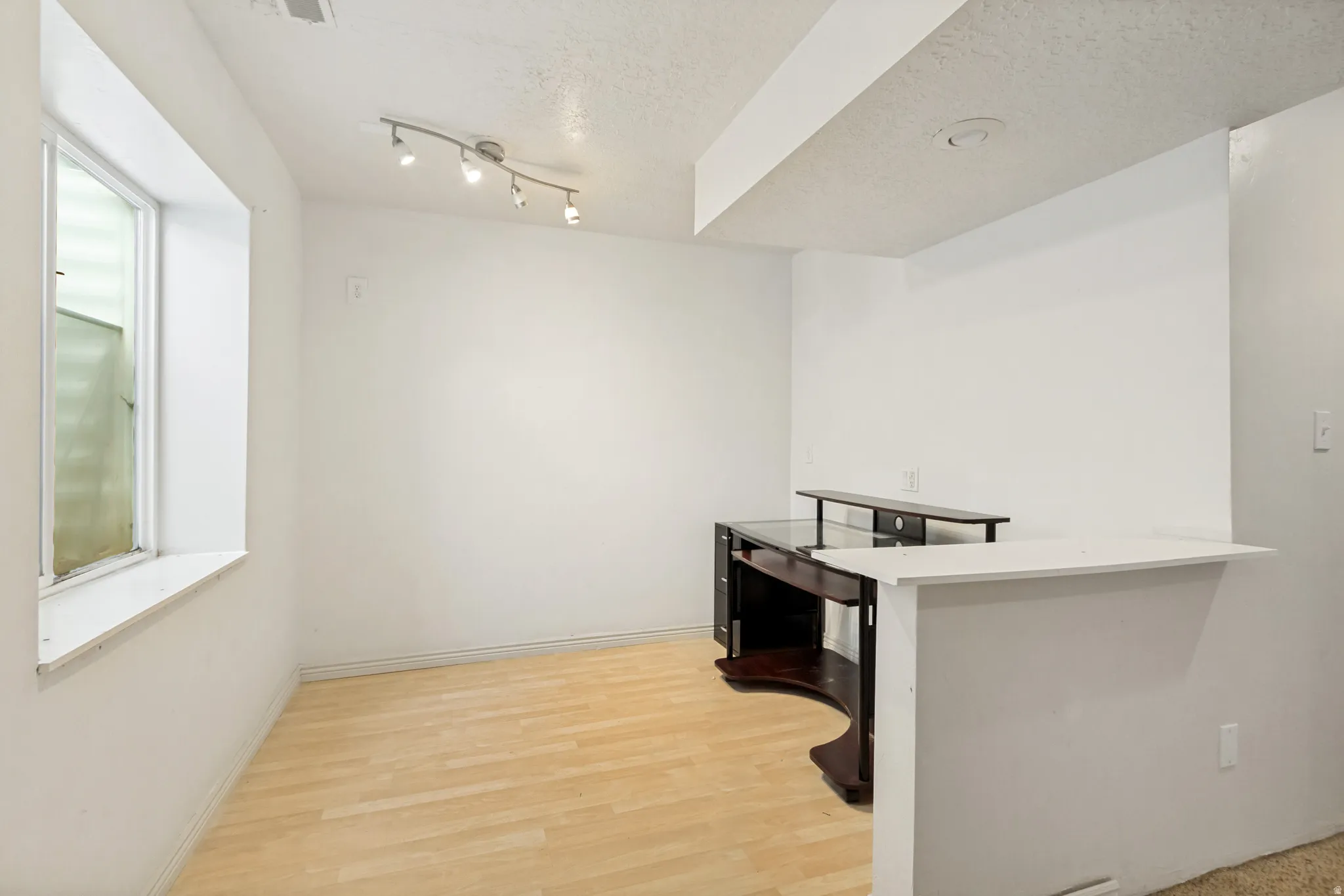 Bright room featuring wood-finish flooring, a built-in counter, and track lighting