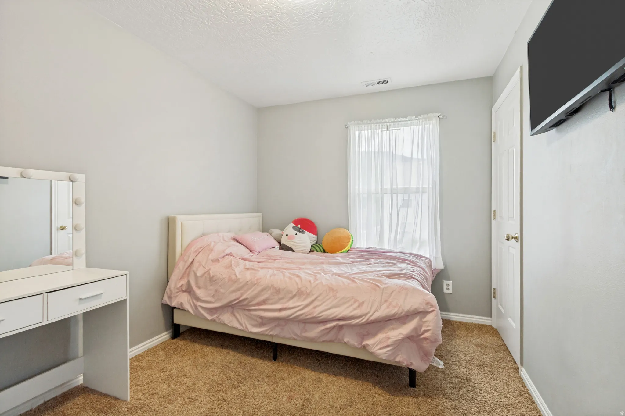 Light gray wall finish with a single window featuring sheer white curtains